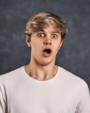 Gri arka planda genç ve yakışıklı bir adam. yüz ifadeleri