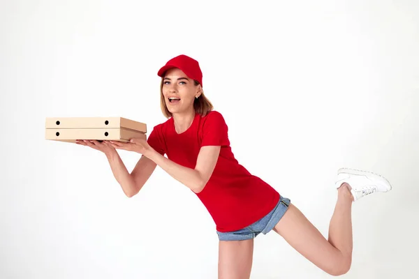 pizza delivery woman in uniform runs in a jump flight holds boxes with pizza on white background. Fast home pizza delivery.