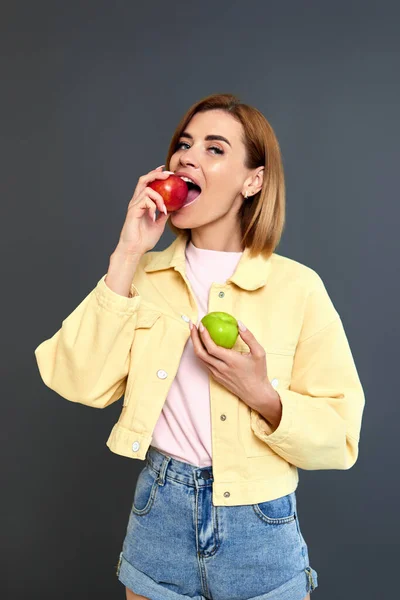 Smiling Blonde Woman Holding Green Red Apples Yellow Background — Foto Stock