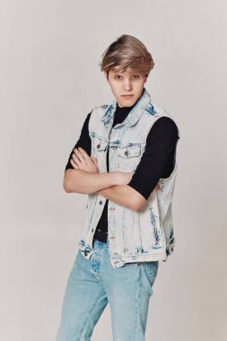 young handsome guy with modern haircut in denim on gray background.