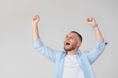 amazed young man celebrating victory on gray background.