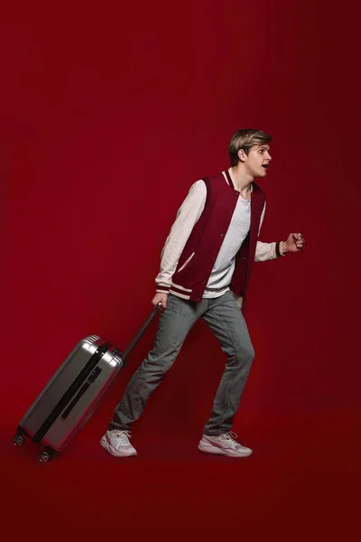 Young Excited Caucasian Man Tourist Walking Suitcase Red Background — Stockfoto
