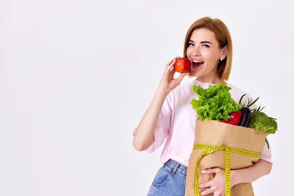 Smiling Caucasian Woman Pink Shirt Paper Bag Vegetables Biting Red — Zdjęcie stockowe
