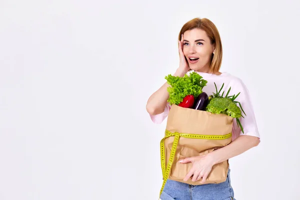 Surprised Slim Woman Hold Paper Bag Vegetables Measuring Tape White — 스톡 사진