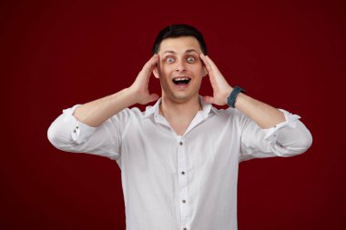 Beyaz gömlekli esmer adam kırmızı arka planda izole edilmiş.