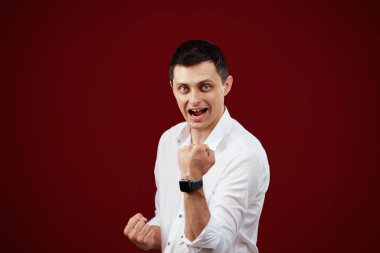 Mutlu genç adam zaferi kırmızı arka planda kutluyor..