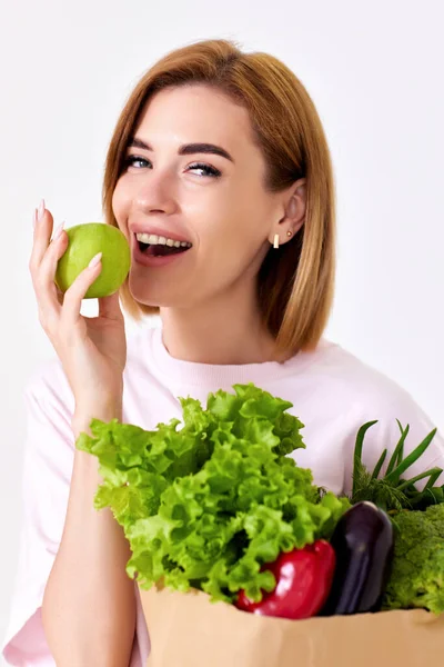 Lächelnde Frau Mit Papiertüte Mit Gemüse Und Beißendem Grünen Apfel — Stockfoto