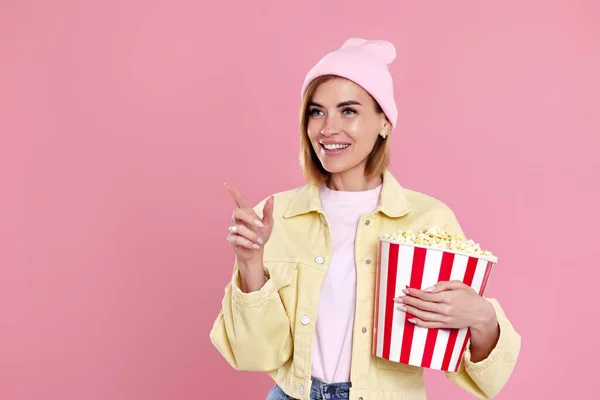 Young Woman Hat Bucket Popcorn Pointing Copy Space Pastel Pink — стоковое фото