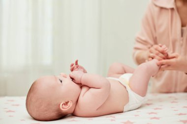 Anne ya da terapist evde bebeğe masaj yapıyor. Anne tarafından bebek bacakları masajı.