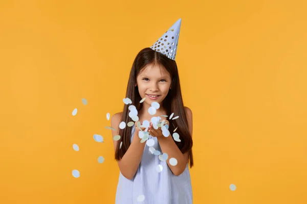 Happy Birthday Child Girl Blowing Confetti Her Hands Yellow Background — Stockfoto
