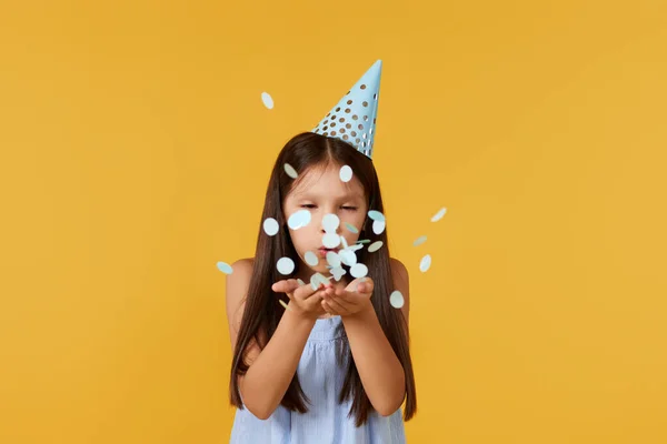 Happy Birthday Child Girl Blowing Confetti Her Hands Yellow Background — Stockfoto