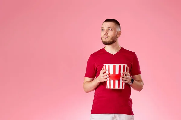 Young Caucasian Man Holding Big Bucket Popcorns Looking Side Pink — 图库照片