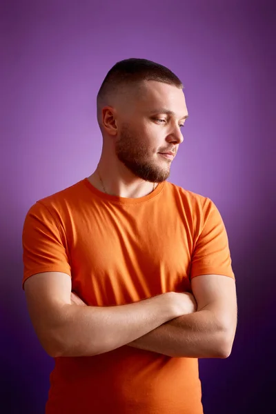 Young Man Orange Shirt Posing Crossed Arms Purple Studio Background — Stockfoto