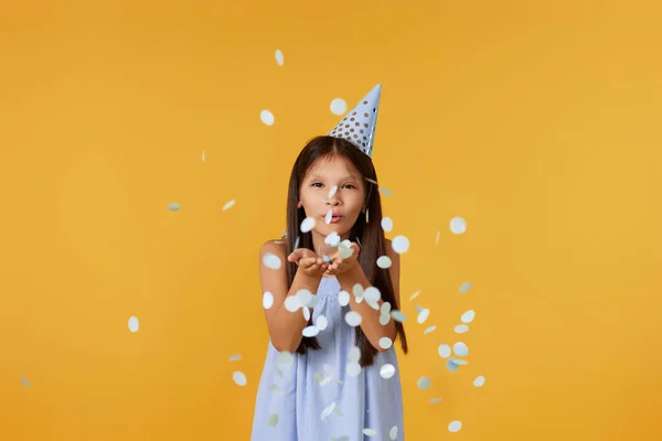 Happy Birthday Child Girl Blowing Confetti Her Hands Yellow Background — Stock fotografie