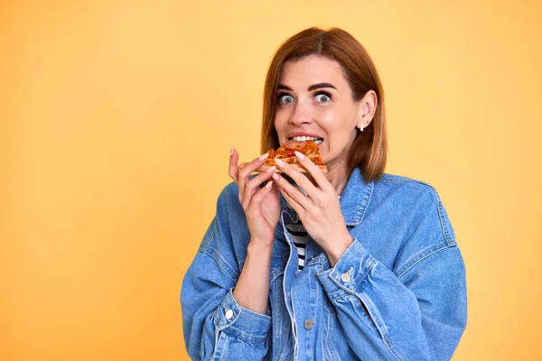 Surprised Young Woman Biting Pizza Slice Yellow Background Copy Space — Stockfoto