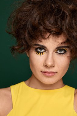 Yeşil arka planda sarı elbiseli yaratıcı kıvırcık kadın..