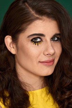 Yeşil arka planda sarı elbiseli yaratıcı kıvırcık kadın..