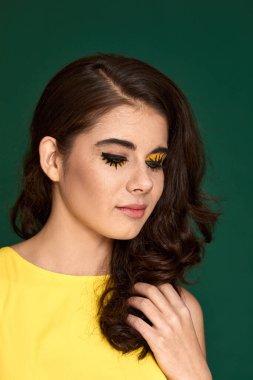 Yeşil arka planda sarı elbiseli yaratıcı kıvırcık kadın..