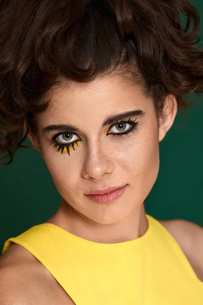 Yeşil arka planda sarı elbiseli yaratıcı kıvırcık kadın..