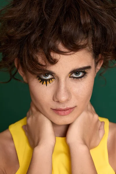 Yeşil arka planda sarı elbiseli yaratıcı kıvırcık kadın..