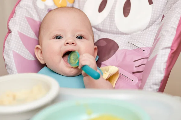 Cute Baby Girl Eating Spoon Baby Chair Kitchen — стоковое фото