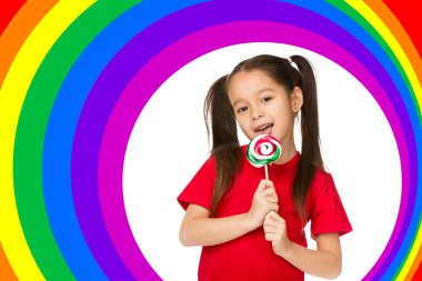 Tatlı küçük kız gökkuşağı arka planında şeker lolipop yiyor.