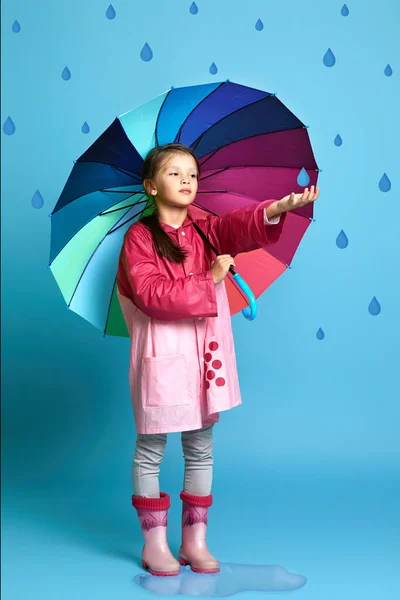 빗속에 분홍빛 비옷을 고무장화를 배경에 고무장화를 비오는지 확인하는 — 스톡 사진