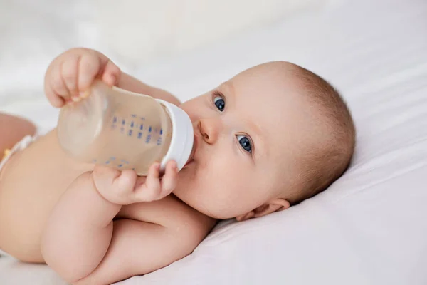 Charming Baby Girl Lies Bed Drinks Water Bottle — Stock Photo, Image