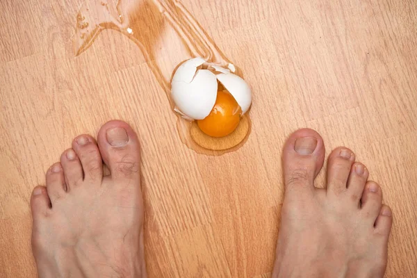 broken egg and feet on the floor in kitchen, top view