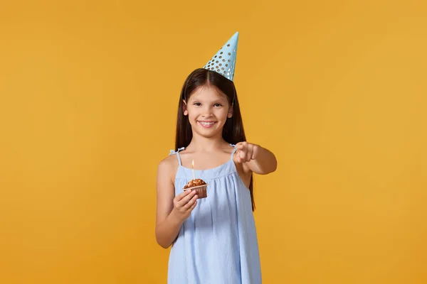 Usmívající Malá Narozeninová Dívka Party Kuželky Čepice Ukazuje Vás Žlutém — Stock fotografie