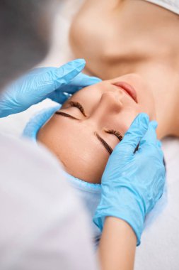 Genç ve güzel bir kadın güzellik salonunda yüz masajı yaptırıyor.