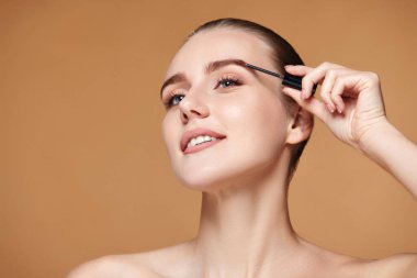 Bej arka planda mükemmel kaşları olan güzel bir kadın. Doğal bir makyaj. Boşluğu kopyala