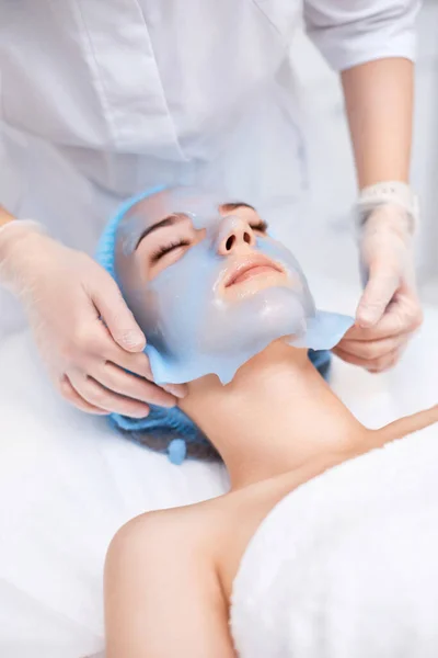 美容师从温泉沙龙的美女脸上摘下蓝色海藻酸钠面罩 温泉治疗 — 图库照片