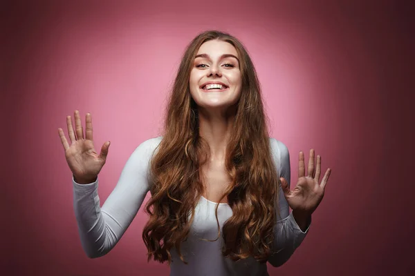 happy woman with strong healthy curly hair dancing on pink background