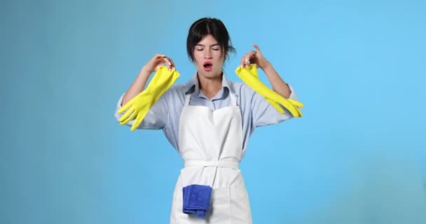 Zmęczona Kobieta Żółtych Gumowych Rękawiczkach Czystszym Fartuchu Ziewa Niebieskim Tle — Wideo stockowe