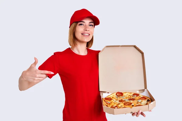 白い背景で孤立したピザを指差す優しいピザ配達の女の子 — ストック写真