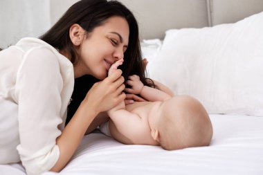 Mutlu anne yatak odasında bebeğini öpüyor. Mutlu aile.