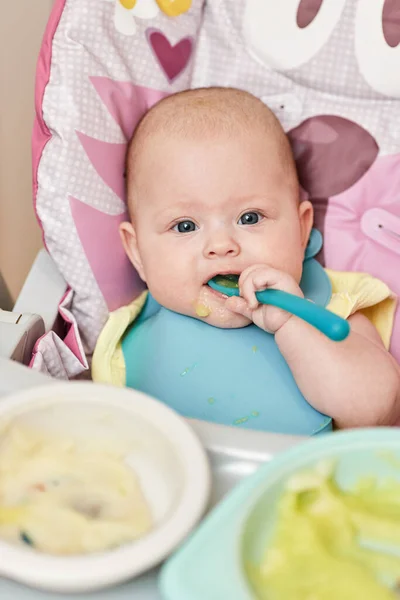 Cute Baby Girl Eating Spoon Baby Chair Kitchen — стоковое фото