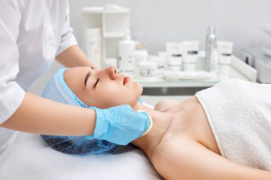 Güzellik uzmanı, genç bir kadının derisini süngerle temizliyor. Mükemmel temizlik, spa tedavisi cilt bakımı.