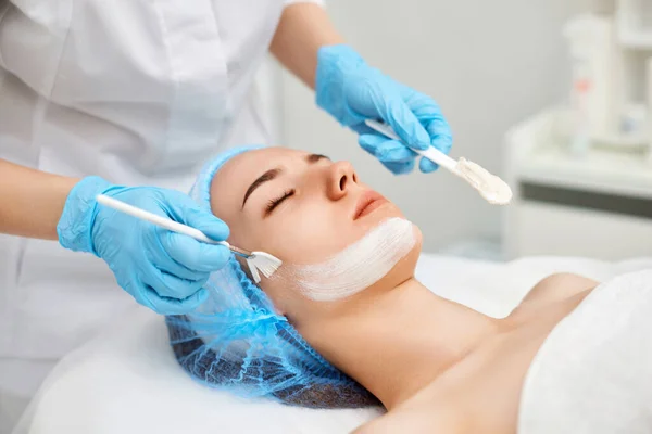 Esteticista Aplica Máscara Cara Hermosa Joven Salón Spa Envejecimiento Concepto — Foto de Stock