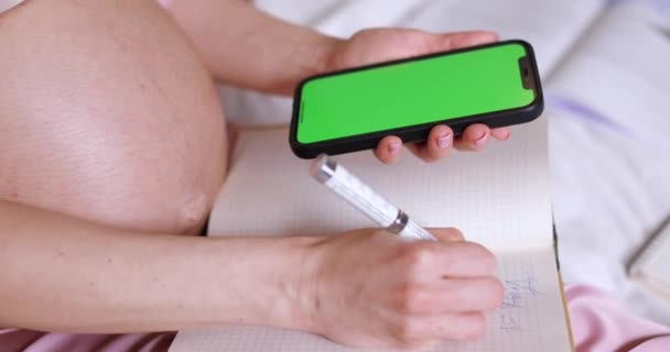 Mulher Grávida Usando Smartphone Com Tela Verde Vazia Escrevendo Notebook — Vídeo de Stock