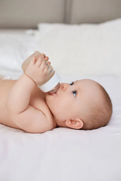 Charming Baby Girl Lies Bed Drinks Water Bottle — Stock Photo, Image