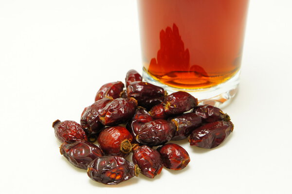 Dried berries of rosehip about a glass with infusion.