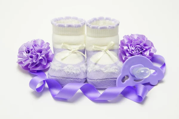 婴儿毛线鞋丁香与奶嘴、 丝带和蝴蝶结. — 图库照片