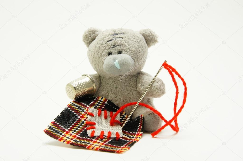 Bear sews a patch.