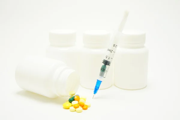 Vaccin. spuiten met de capsule en de pot met pillen tegen witte potten. — Stockfoto