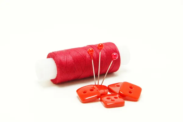 kırmızı iplik ile iğne ve kırmızı düğme.