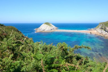 Güzel mavi gökyüzü olan sakin bir denizin yanındaki sarp kayalıklar