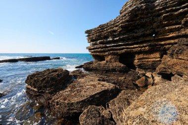 Derin mavi denizi ve berrak mavi gökyüzü olan sarp kayalıklar.