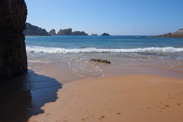 stock image A quiet fine sandy beach with cliffs in the background